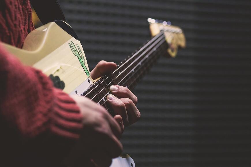 Nærbilde av hender som holder og spiller på en elgitar.