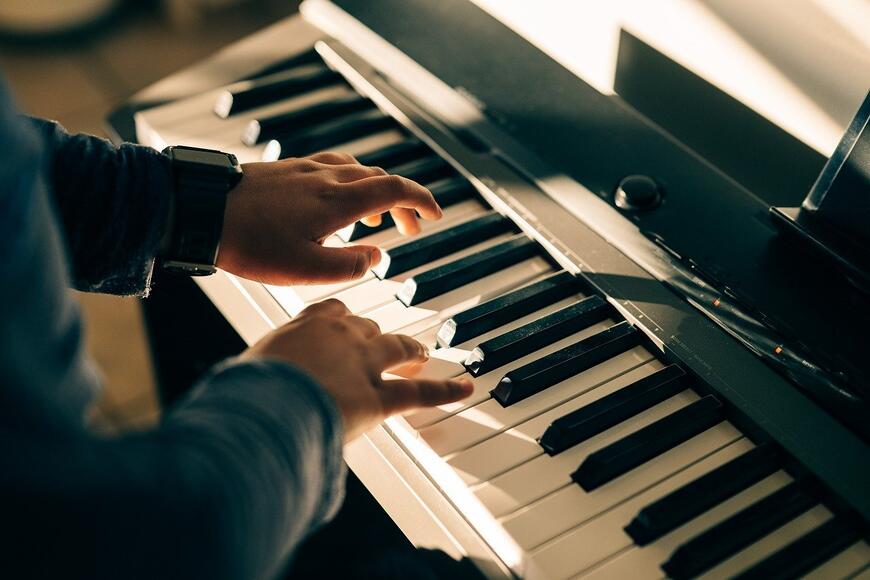 Barnehender som spiller på et lite piano.