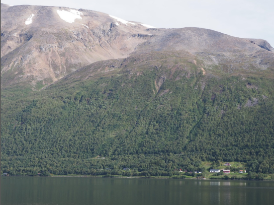 Bildet viser Mettevoll på sommerstid. Et bratt fjellterreng, og et vann.