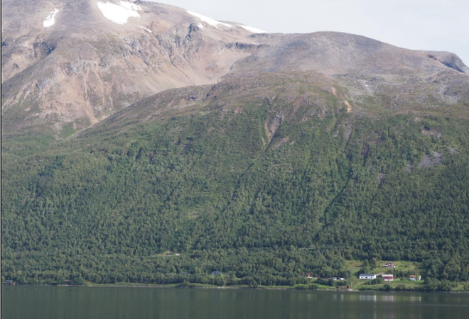 Bildet viser Mettevoll på sommerstid. Et bratt fjellterreng, og et vann.