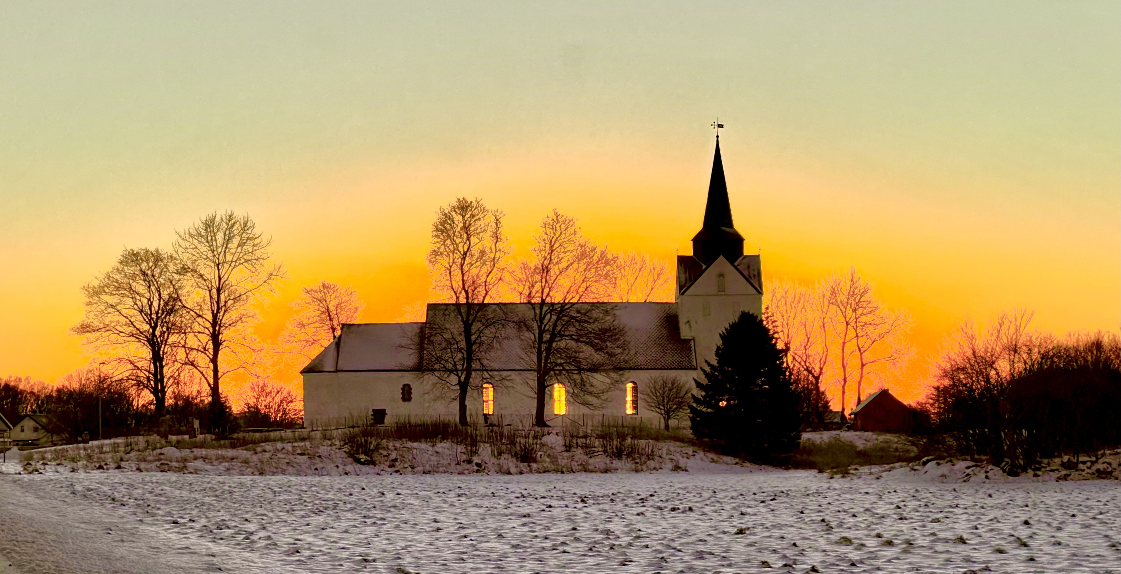 Mektig lys på Herøy kirke ved solsnu. (Foto: Bente Lien)