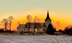 Mektig lys på Herøy kirke ved solsnu. (Foto: Bente Lien)