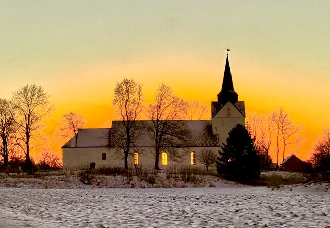 Mektig lys på Herøy kirke ved solsnu. (Foto: Bente Lien)