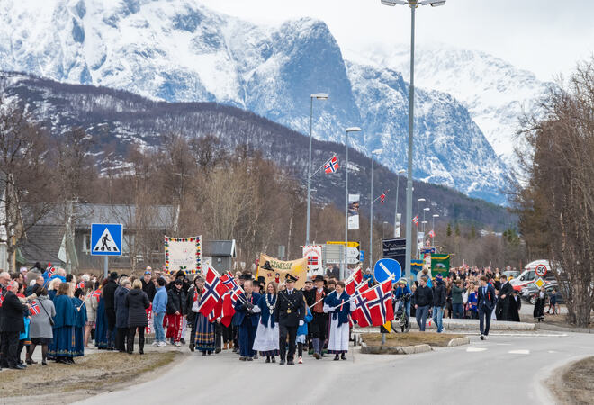 Bildet viser et 17. mai tog med politiet i front, tetter etterfulgt av ordfører og resten av toget. Det er mange glade folk.