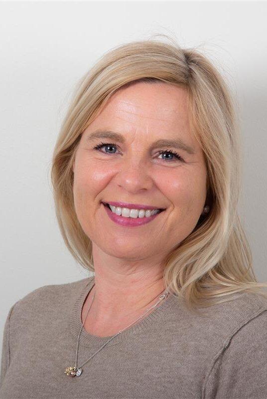 Kvinne med langt lyst hår og beige genser
