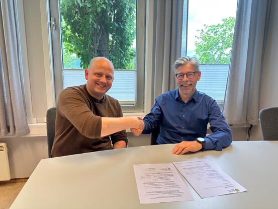 Bilde av ordfører Birger Holand og kommunedirektør Per Bjørn Holm-Varsi som tar hverandre i hendene etter signering av lederavtalen.
