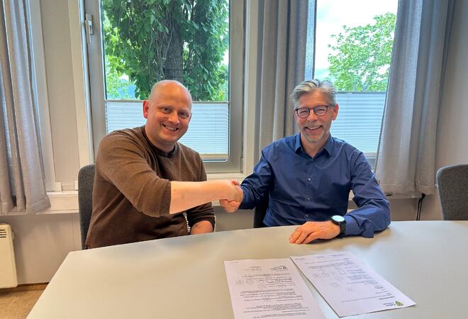 Bilde av ordfører Birger Holand og kommunedirektør Per Bjørn Holm-Varsi som tar hverandre i hendene etter signering av lederavtalen.