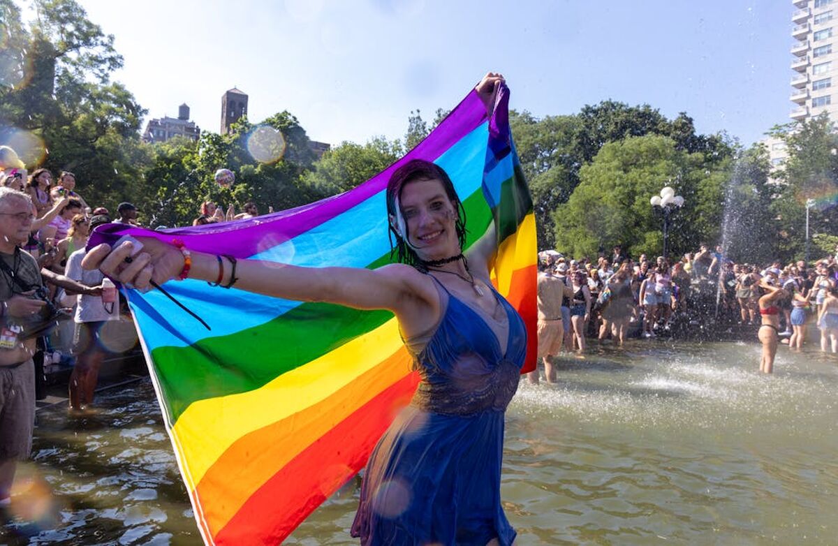 Pride, kvinne i blå kjole med flagget bak seg