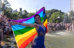 Pride, kvinne i blå kjole med flagget bak seg