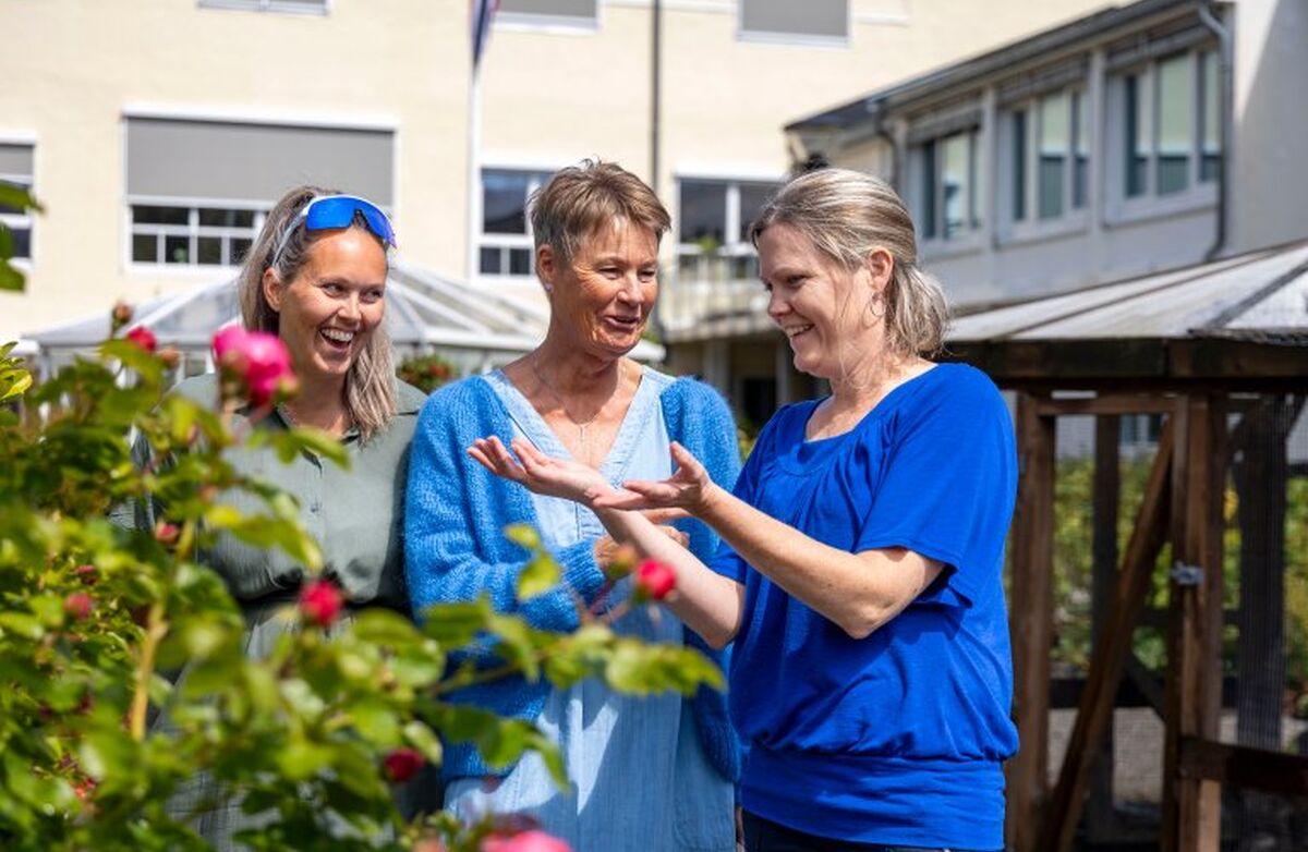 Tre kvinner i samtale i det grønne. Smil og latter.
