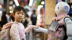 Liten japansk eller kinesisk jente hilser på robot.