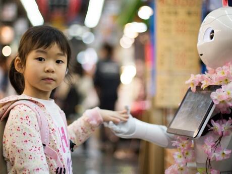Liten japansk eller kinesisk jente hilser på robot.