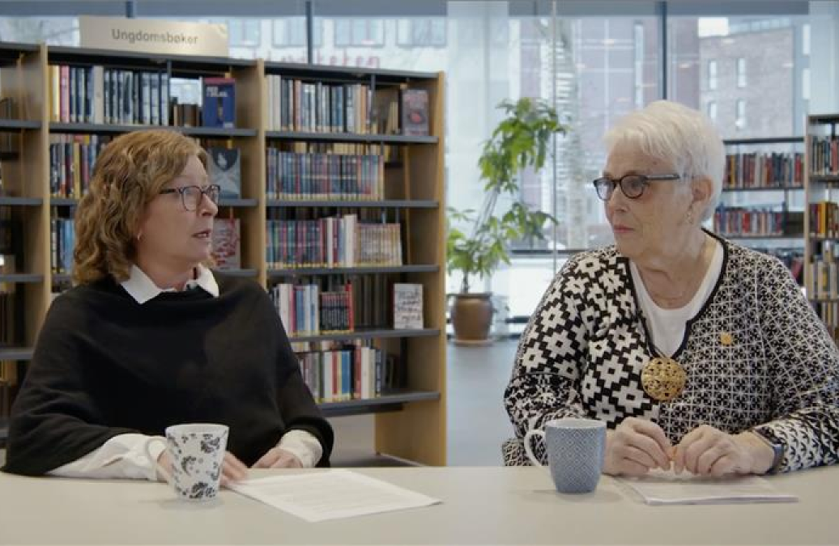 Formannskapssekretær Trude Paulsen (t.v) og eldrerådsleder Kari Ørnø og i Indre Østfold kommune sitter på et bibliotek.