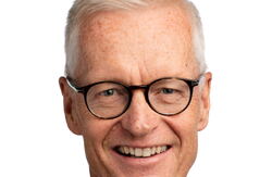Jørn Leonardsen er IT-direktør i Skatteetaten. Foto: Skatteetaten. Kort grått hår, blå skjorte, lys brun dress, blå øyne, smiler