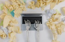 Skjelletthender skriver på et tastatur, blader fra trærne rundt tastaturet.