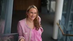 Smilende kvinne med lyst hå, rosa bluse