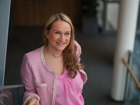 Smilende kvinne med lyst hå, rosa bluse