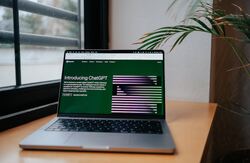 ChatGPT på en skjerm på et skrivebord, plante i rommet