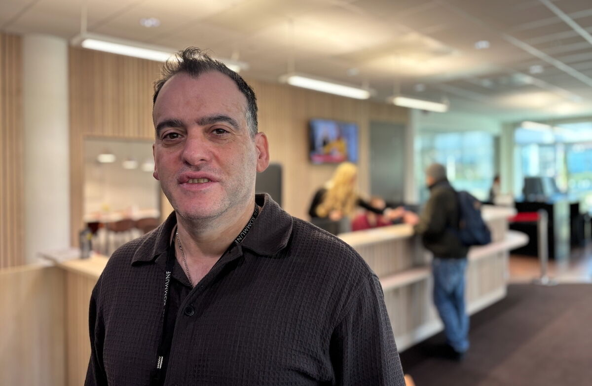 – Hovedspråket er norsk, men virkeligheten er flerspråklig. Får vi til gode møter i skranken, får vi også mer tillit — og bedre tjenester for alle, sa Reza Arash Mahootchi. Foto: Eva Hille Mann med iransk bakgrunn, vestlig kledd, står i en korridor i et kontormiljø.