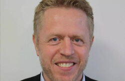 – Det nye KI-søket hjelper deg å finne svar raskt og presist, uten at du trenger å klikke deg gjennom mange sider, forteller direktør for tjenesteutvikling i Arkivverket, Ivar Holm. Foto: Arkivverket Middelaldrende mann med krøller i håret, smiler