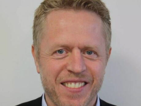 Middelaldrende mann med krøller i håret, smiler