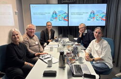 Menn og kvinner rundt et bord, ser inn i kamera