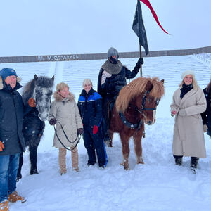 En gruppe mennesker rundt to islandshester med en rytter i brynje og med hjelm