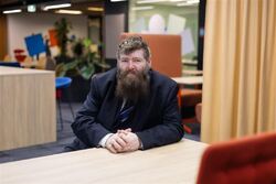 Raymond André Hagen har skjegg og dress, og sitter på et kontor. Håret er halvmørkt med grå stenk.