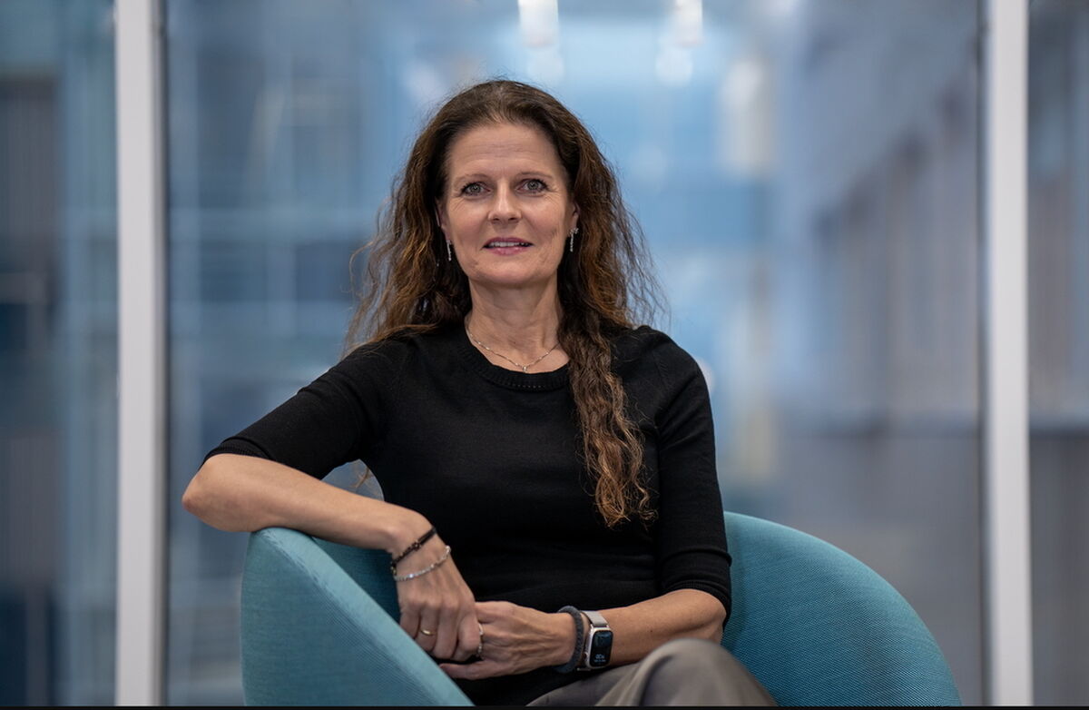 Smilende kvinne med langt hår sitter i stol