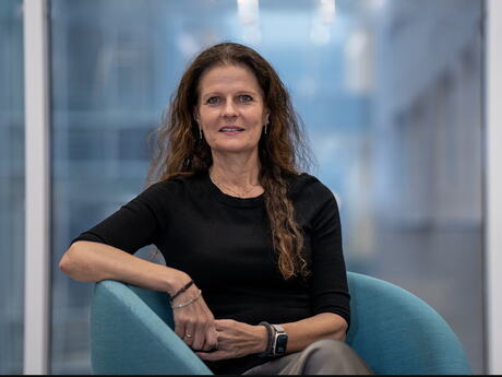 Smilende kvinne med langt hår sitter i stol