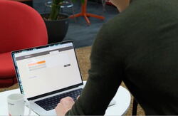 En mann sett bakfra sitter med en åpen PC-skjerm