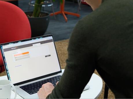 En mann sett bakfra sitter med en åpen PC-skjerm