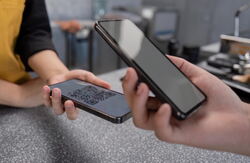 Sammen med Politiet og Utlendingsdirektoratet gjennomfører Digdir nå en utredning om hvilket konsept Norge skal satse på, blant annet hvordan staten skal samarbeide med privat sektor for å kunne lansere lommeboken. Illustrasjonsfoto: Envato Elements To personer der vi bare ser deler av kroppen og en hånd fra hver som holder på en mobil ganske nær hverandre.