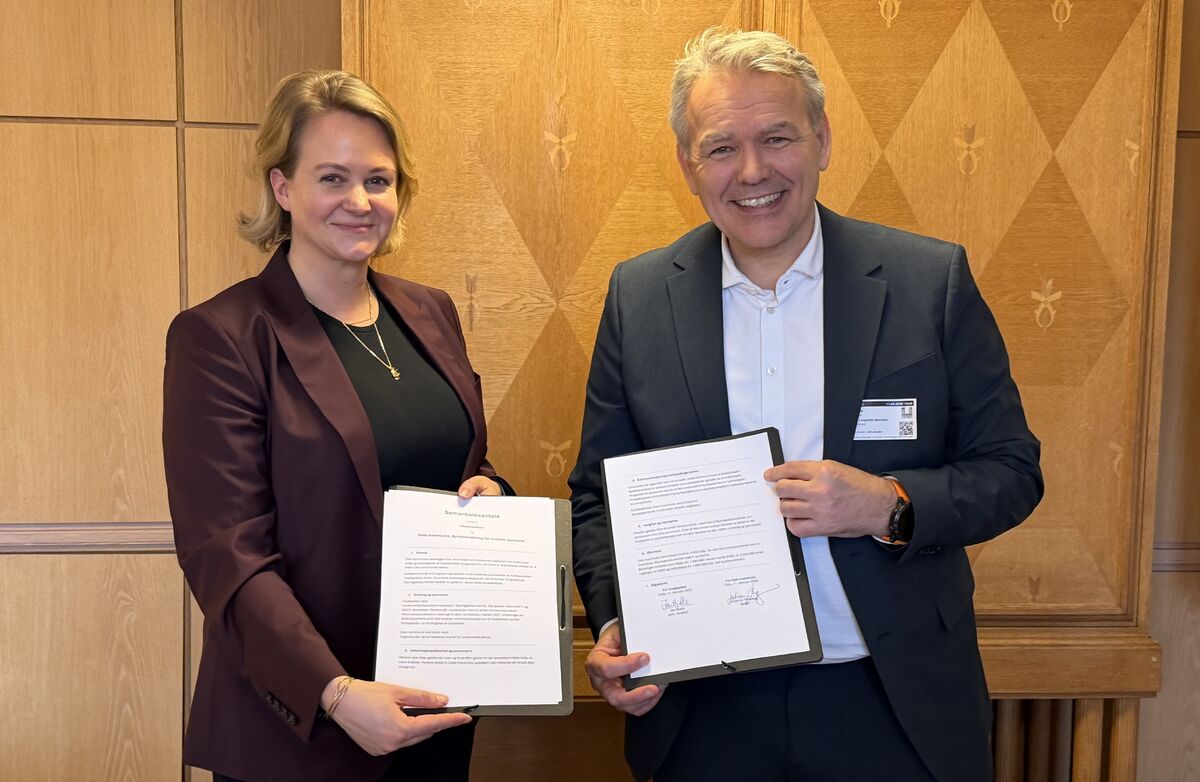 En dame og mann som holder i samarbeidsavtalen.