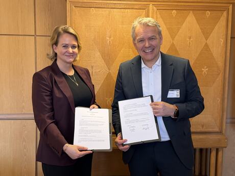 En dame og mann som holder i samarbeidsavtalen.