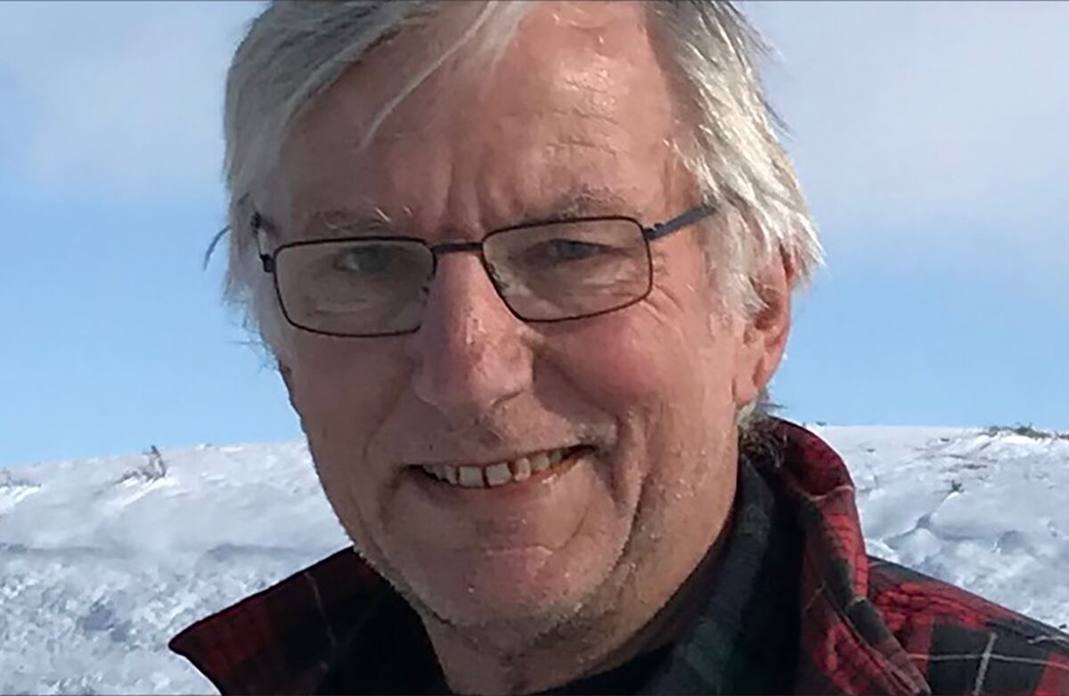 En eldre mann utendsørs omgitt av snø, muligens på fjellet.