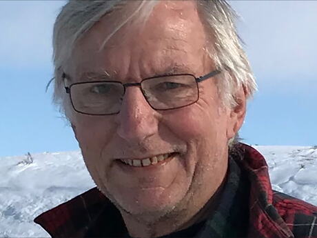 En eldre mann utendsørs omgitt av snø, muligens på fjellet.