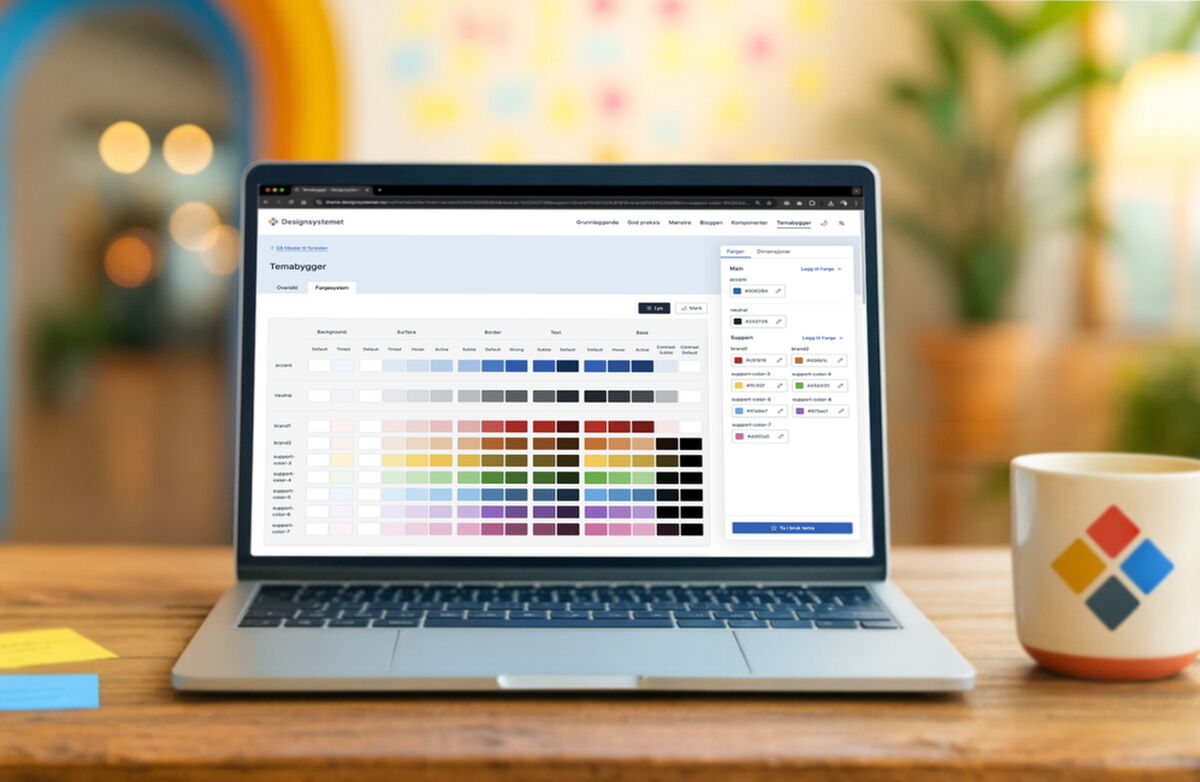 Designsystemet brukes av blant annet: Mattilsynet, Brønnøysundregistrene, Utdanningsdirektoratet, KS Digital, Enova, Tolletaten, Avinor, Arbeidstilsynet, Riksrevisjonen, Kystverket, Innovasjon Norge og flere kommuner. Foto: digdir En åpen PC-skjerm på et trebord viser designsystemet. På bordet er det postit-lapper i forskjellige farger på venstre side og en kaffekopp på høyre side.