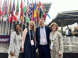 Deltakerne på turen fotografert untendørs, med mange flagg i bakgrunnen.