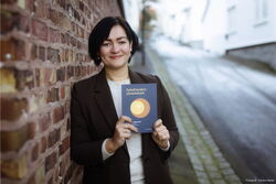 Unn Therese Omdal holder opp boka som hun har skrevet.