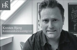 Poenget til Kresten Bjerg var ikke at KI er ubrukelig, men at den må styres hardere – med mer presise og språklig informerte instruksjoner enn typiske generelle skriveråd. Foto: Privat Bildet er et svart-hvitt portrett av en mann som sitter innendørs og ser rett inn i kamera. Til venstre i bildet ligger en halvtransparent tekstboks med navnet og tittelen hans: «Kresten Bjerg – Kommunikationsrådgiver». Øverst til venstre er det o