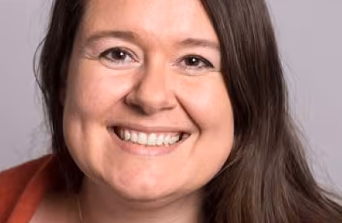 Klara Sjo brukte mykje humor i foredraget sitt og understreka at språket alltid har vore i rørsle. Det har alltid lånt, vridd seg, tilpassa seg og teke opp i seg nye lag. Foto: UiB Smilende kvinne med langt mellommørkt hår.