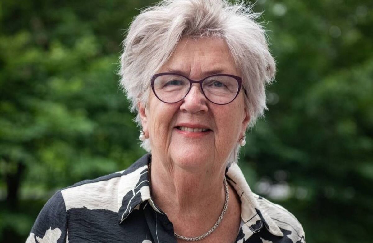 Eldre kvinne halvkort grått hår med grønn bakgrunn