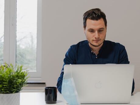 Ung mann med litt skjeggvekst sitter ved en skjerm på et lyst kontor.