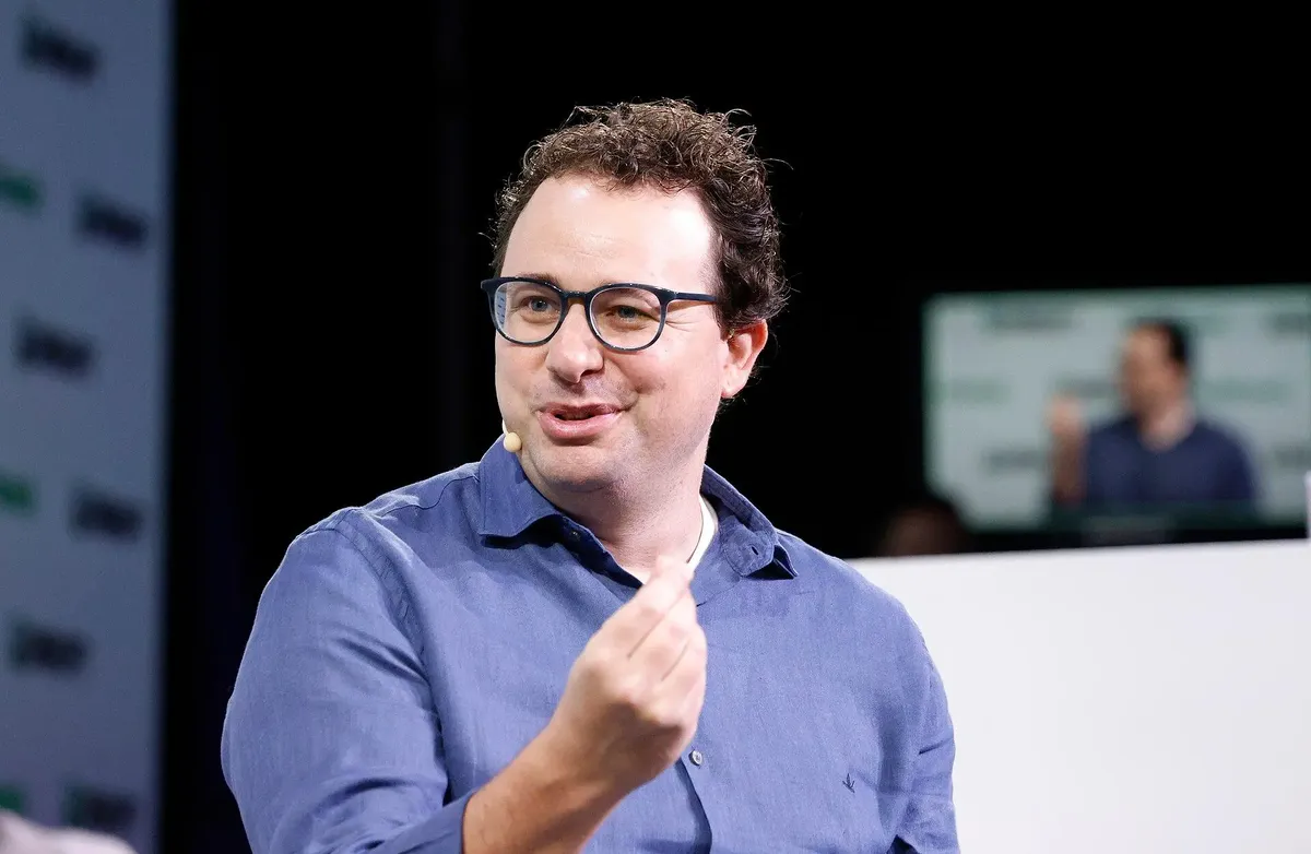 Mann med brunt krøllete hår og lilla skjorte, virker engasjert