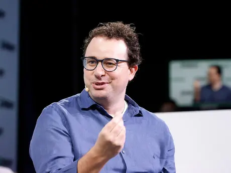 Mann med brunt krøllete hår og lilla skjorte, virker engasjert