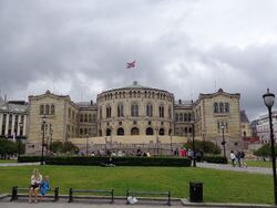 Stortingsbygningen, med en mor og et barn i forgrunnen.