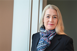 Kvinne med lyst hår ser inn i kameraet.