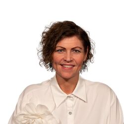 Bildet viser en smilende Jakobe Juul i hvit bluse.