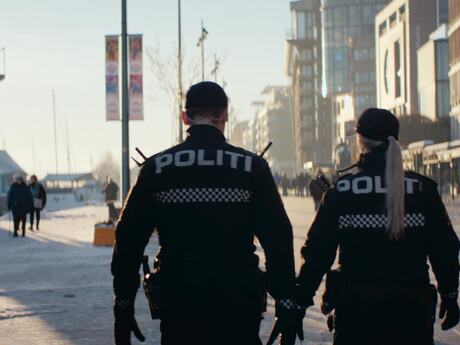 To personer fra politiet sett bakfra i et bylandskap.